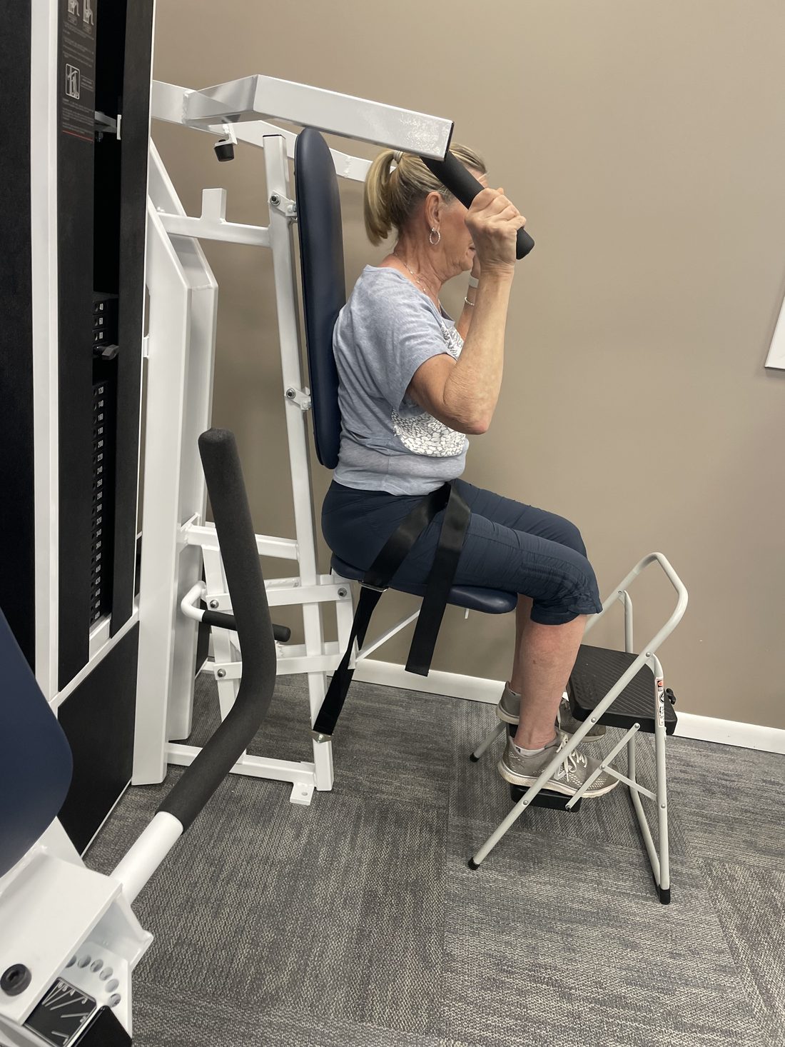 Client on overhead press machine